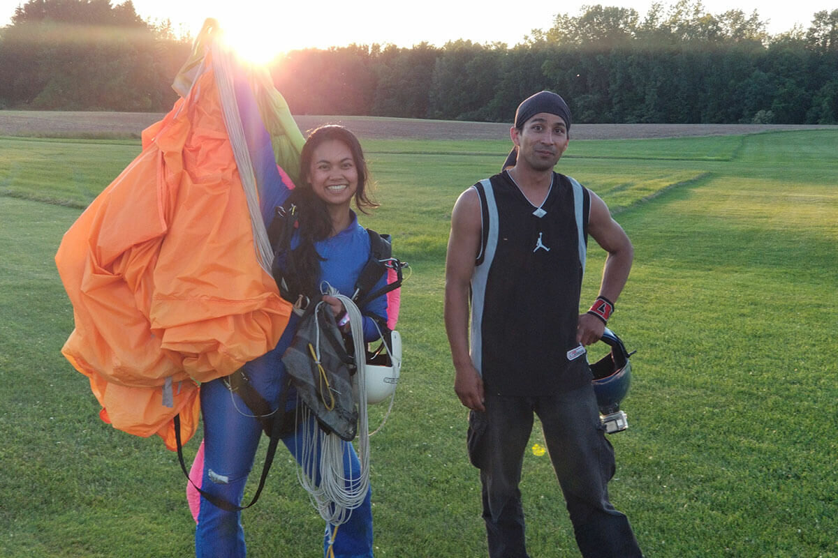Smiling female AFF student holds deployed canopy after skydive.