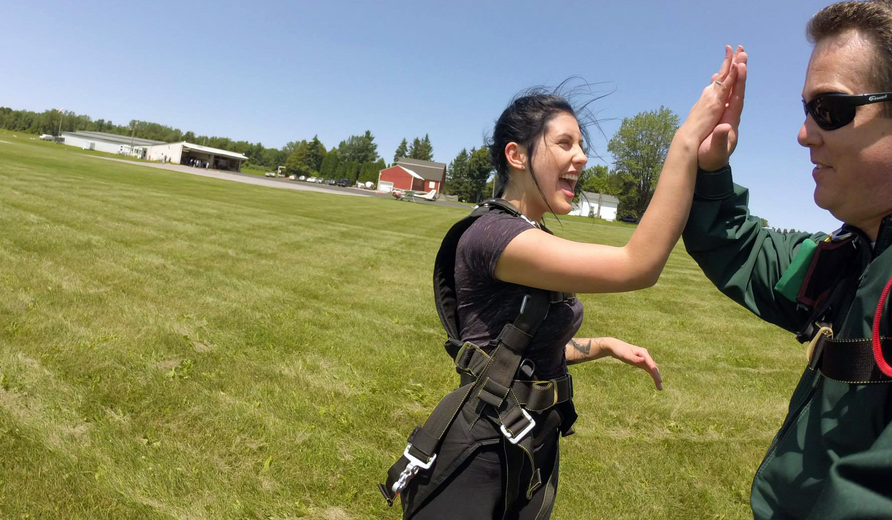 2 Skydivers - some of the happiest people in the world - high five each other after landing.
