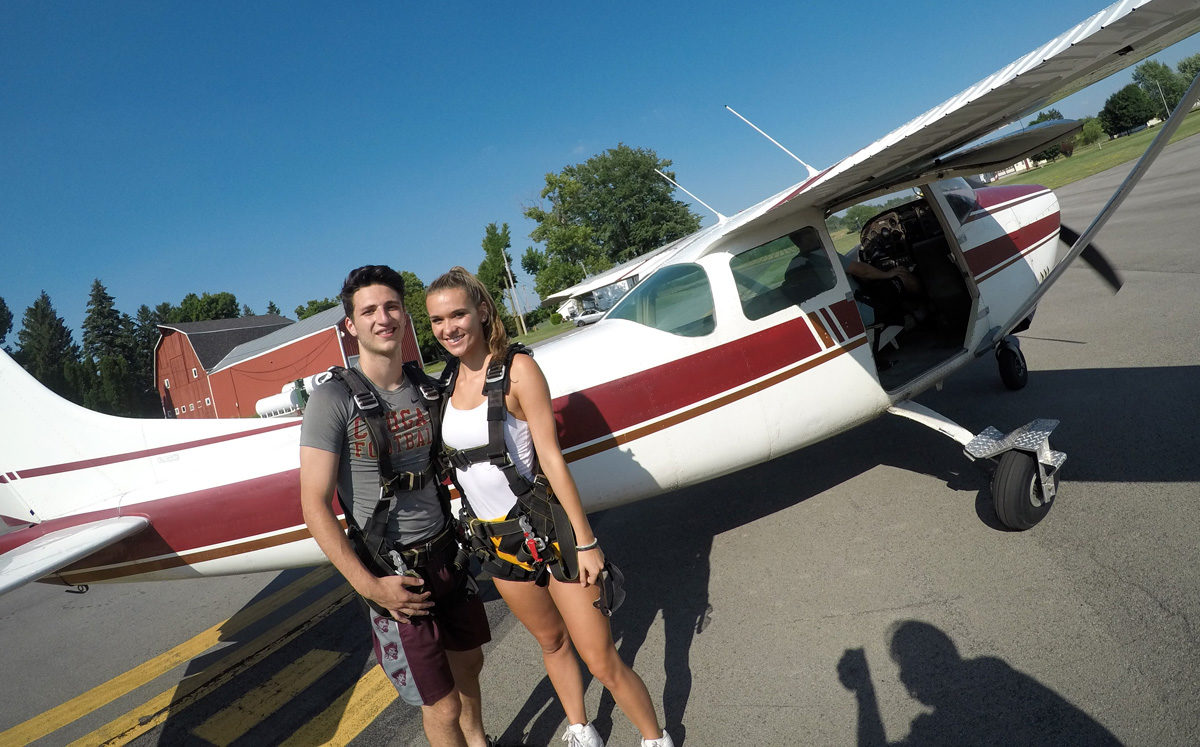 Two young skydivers pose beside plane at WNY Skydiving